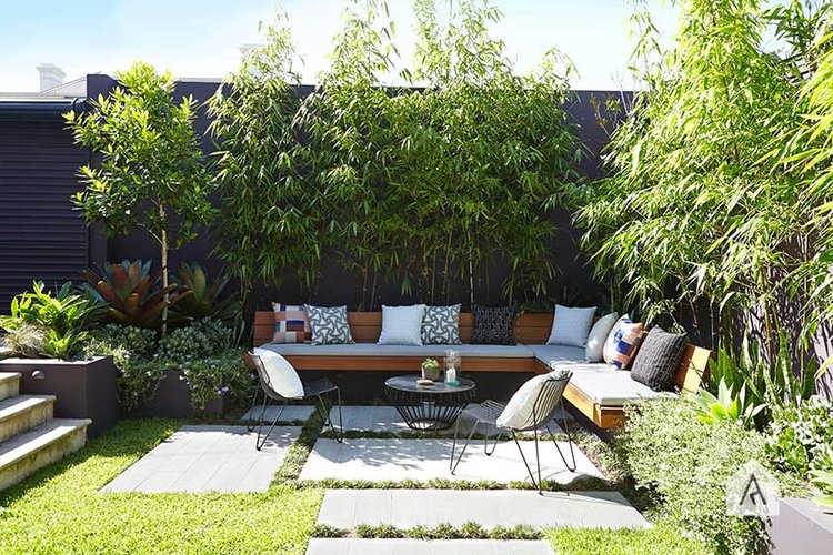 This great built-in furniture piece hides in the corner of the yard *and* has pavers to boot! I love the mid-century flair and mix of throws. The wall of bamboo trees also softens the hard spaces just behind it from making the patio too hard and harsh. #backyard inspiration via www.L-2-Design.com