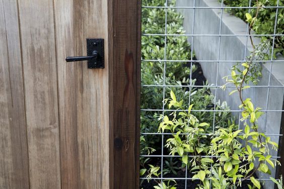 This modern wire fence integrates metal and wood wonderfully. The hog wire allows flowering vines to grow while the wood door provides security of entry. The only downside of this design is the vertical door planks. Fence #inspiration via www.L-2-Design.com